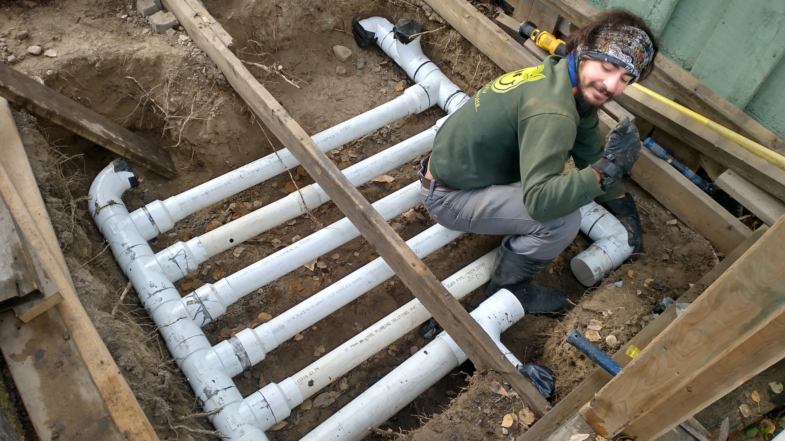 Field technician installing perforated sewer pipe  to allow solar heat to be blown and stored underground with insulation cover.